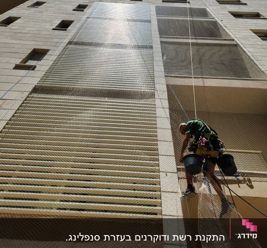 אדם מתקין רשת על בניין גבוה למניעת יונים